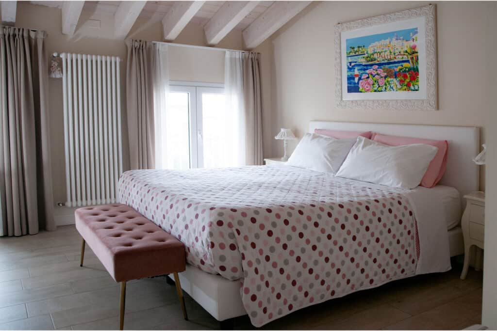 Camera con letto beige e dettagli rosa, ambiente accogliente e luminoso.